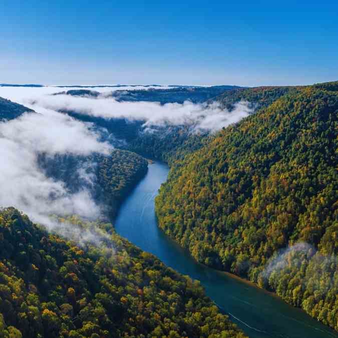 Aerial view of West Virginia featuring dense forests under a clear blue sky.
