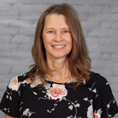 A woman wearing a black floral shirt is smiling for the camera.