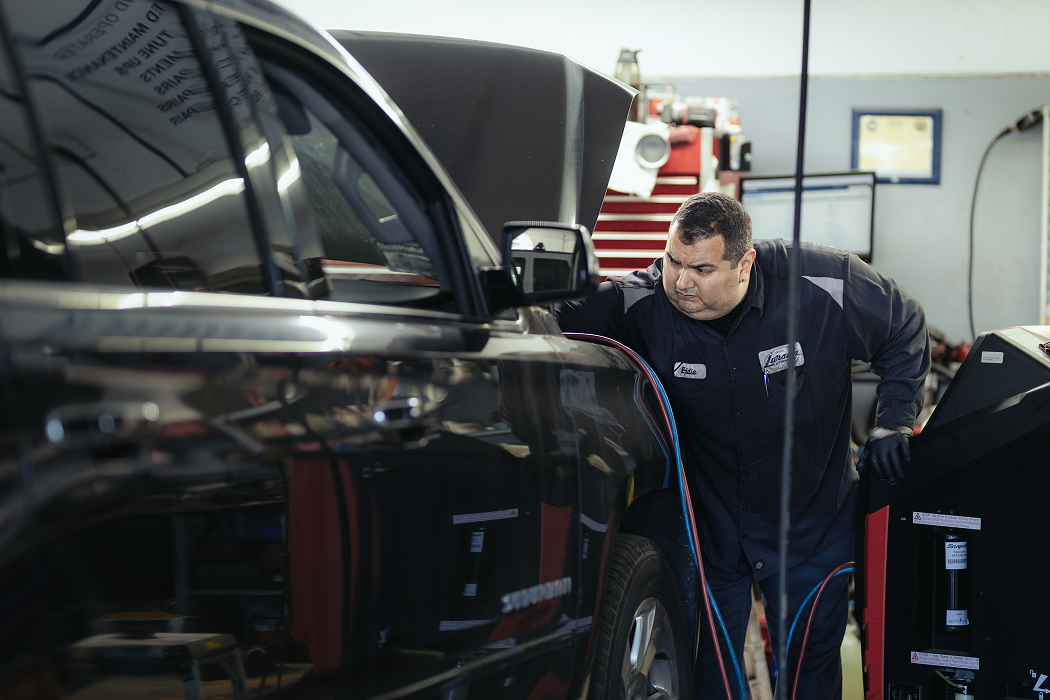 A man is working on a black truck in a garage | Larsen Automotive