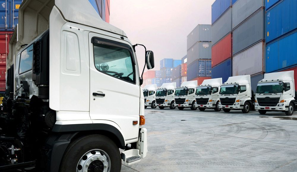 A Row of Trucks Are Parked in a Parking Lot in Front of Shipping Containers — Automotive Repair Centre In Garbutt, QLD