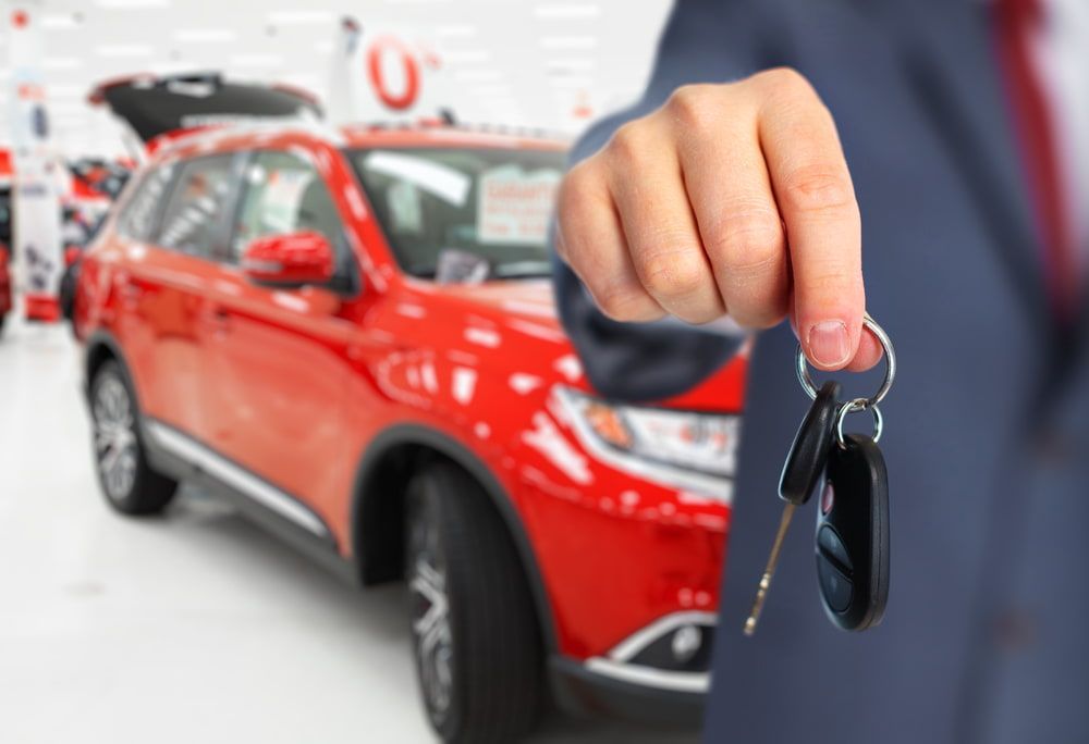 A Man Is Holding A Car Key In Front Of A Red Car — Automotive Repair Centre In Garbutt, QLD