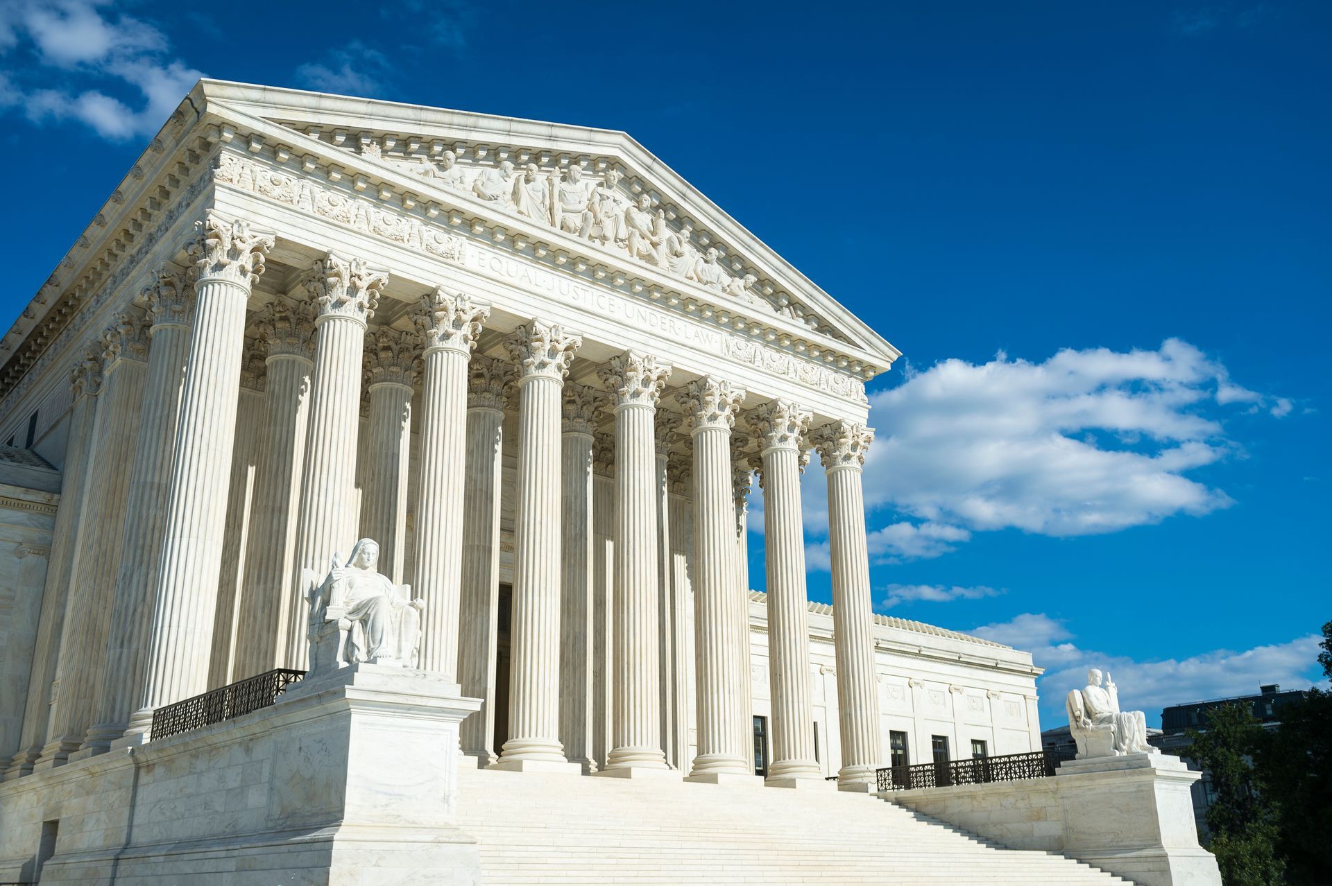 Exterior of the U.S. Supreme Court building with columns and steps, against a blue sky with clouds.