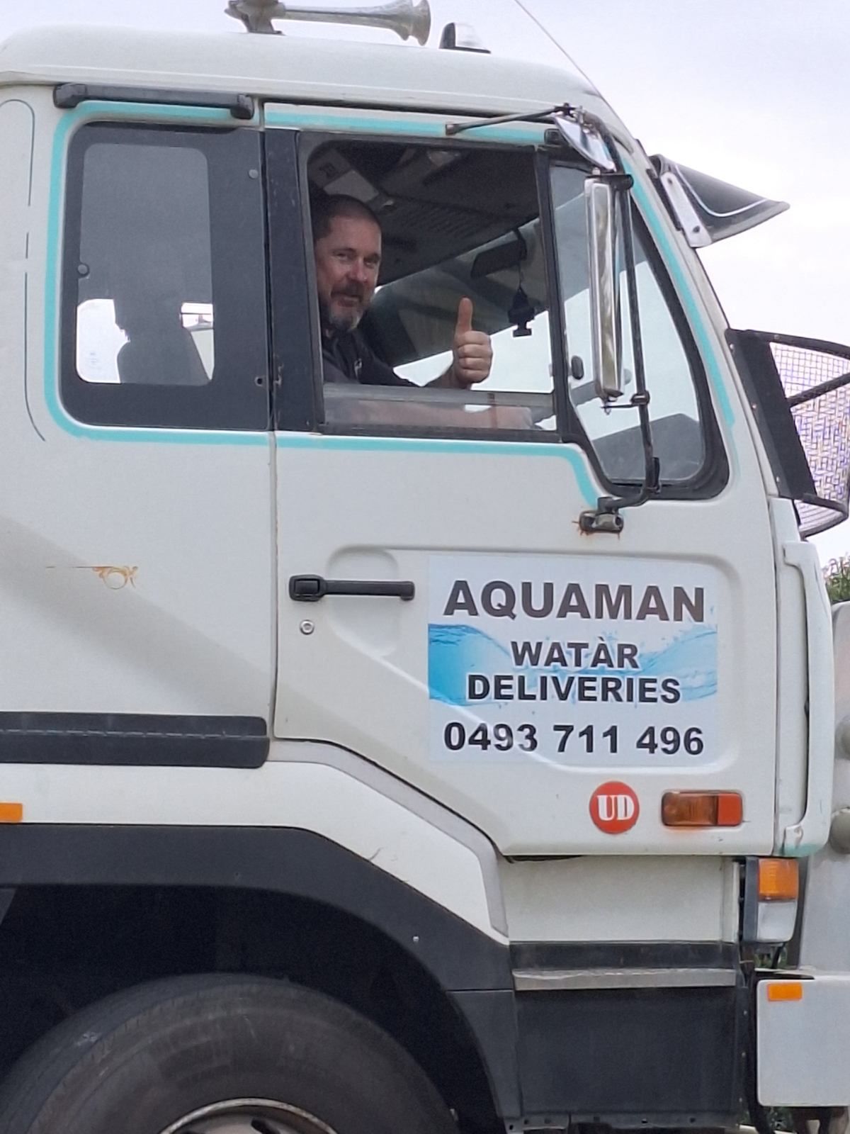 A Man Is Driving An Aquaman Water Delivery Truck — Aquaman Watàr Deliveries In Bald Knob, QLD