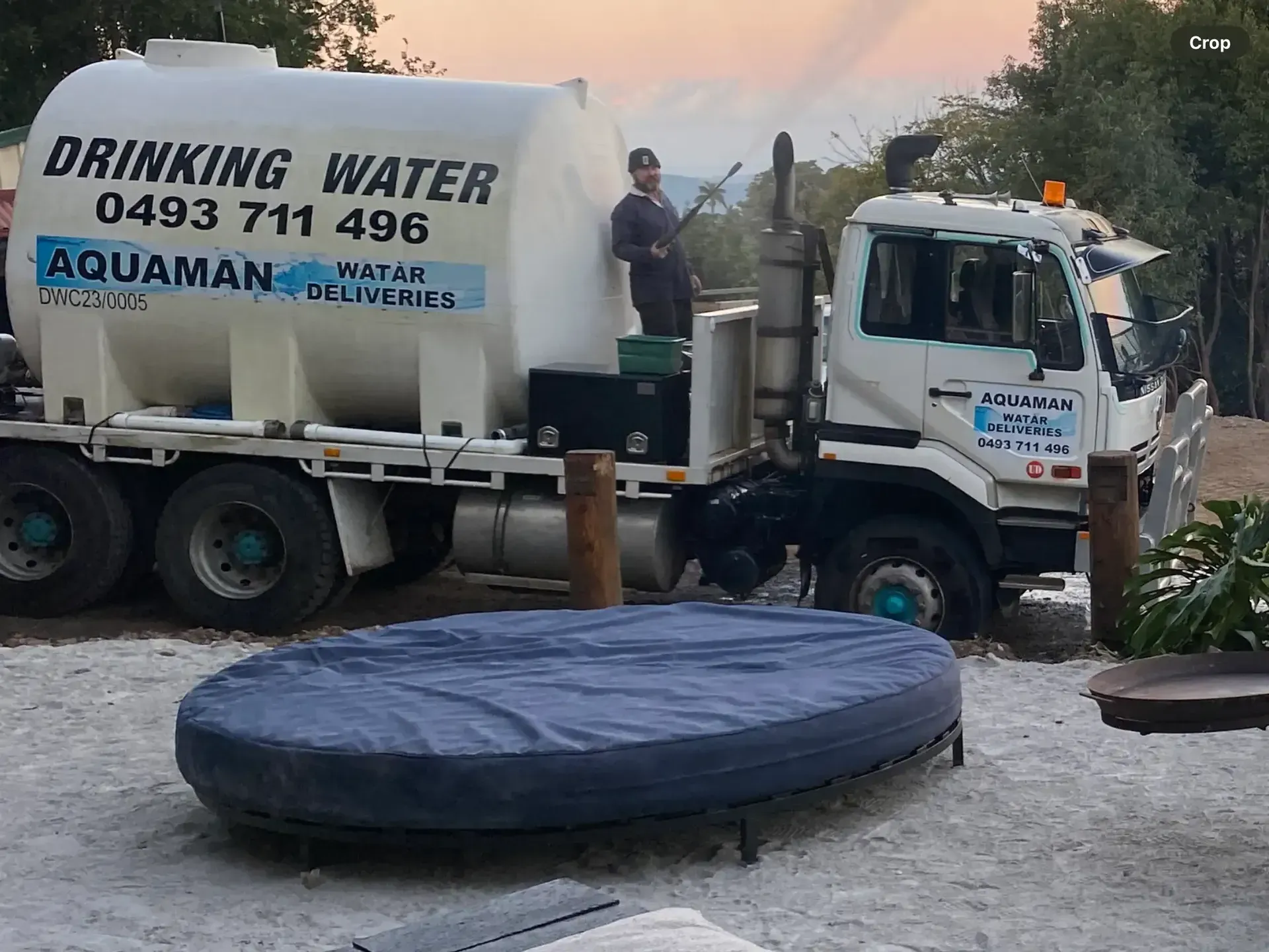 A Man Is Standing On The Back Of A Drinking Water Truck — Aquaman Watàr Deliveries In Bald Knob, QLD