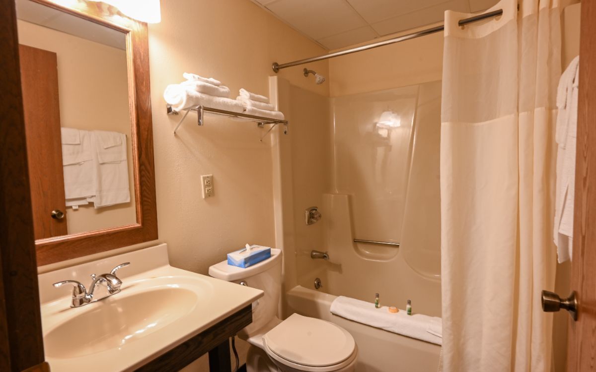 Bathroom with a sink, toilet, bathtub, towels, and neutral walls.