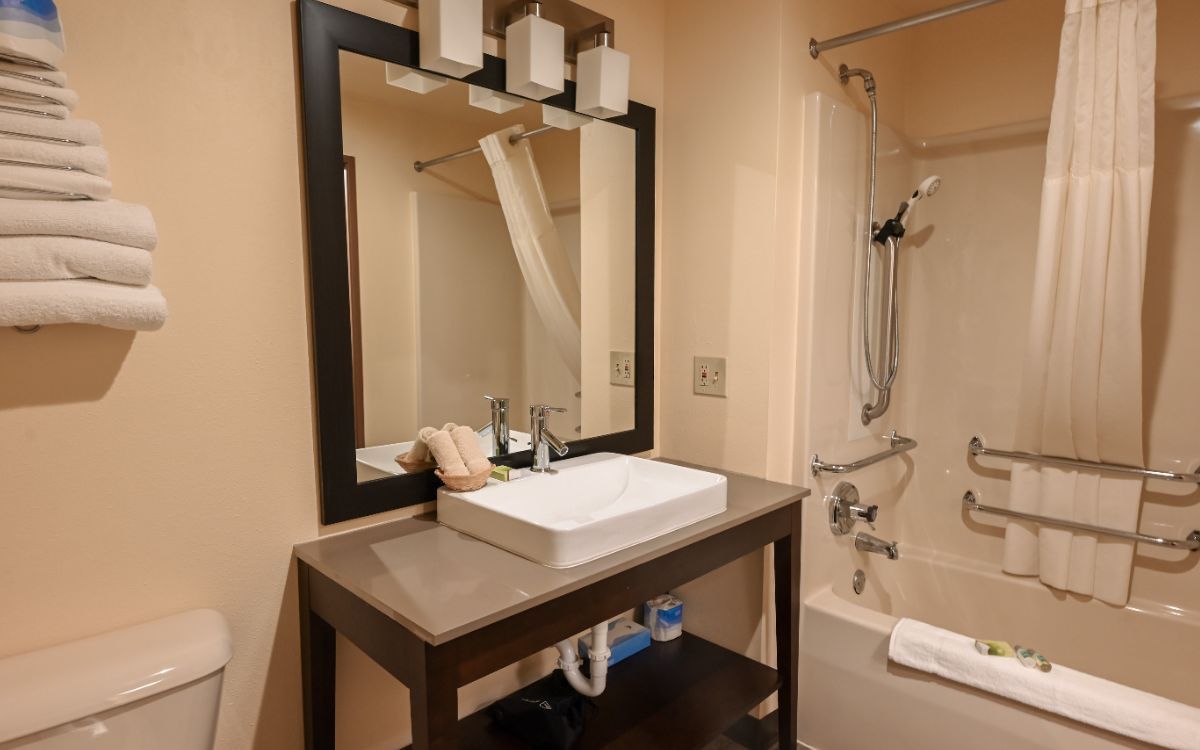 Bathroom with vanity, mirror, tub, toilet, and towel rack.