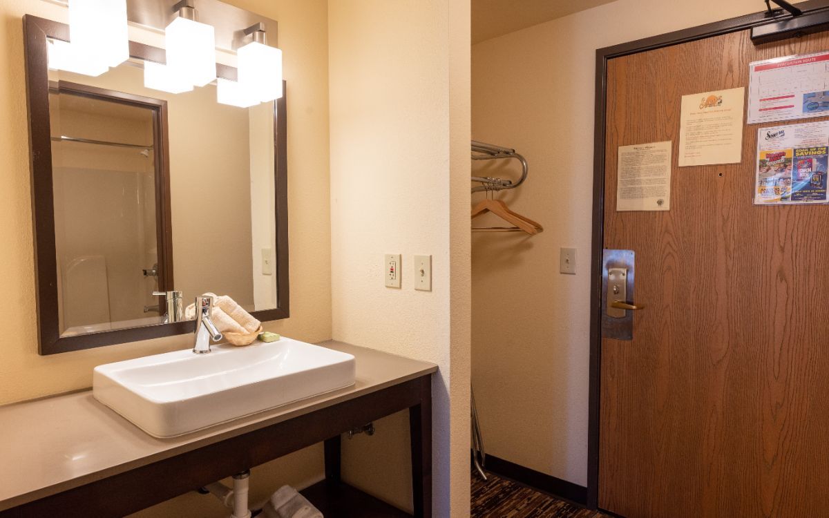 Bathroom with a rectangular sink, mirror, and a closed wooden door.