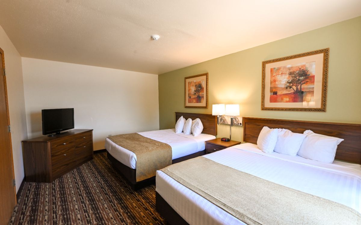 A hotel room with a king size bed and a ceiling fan.