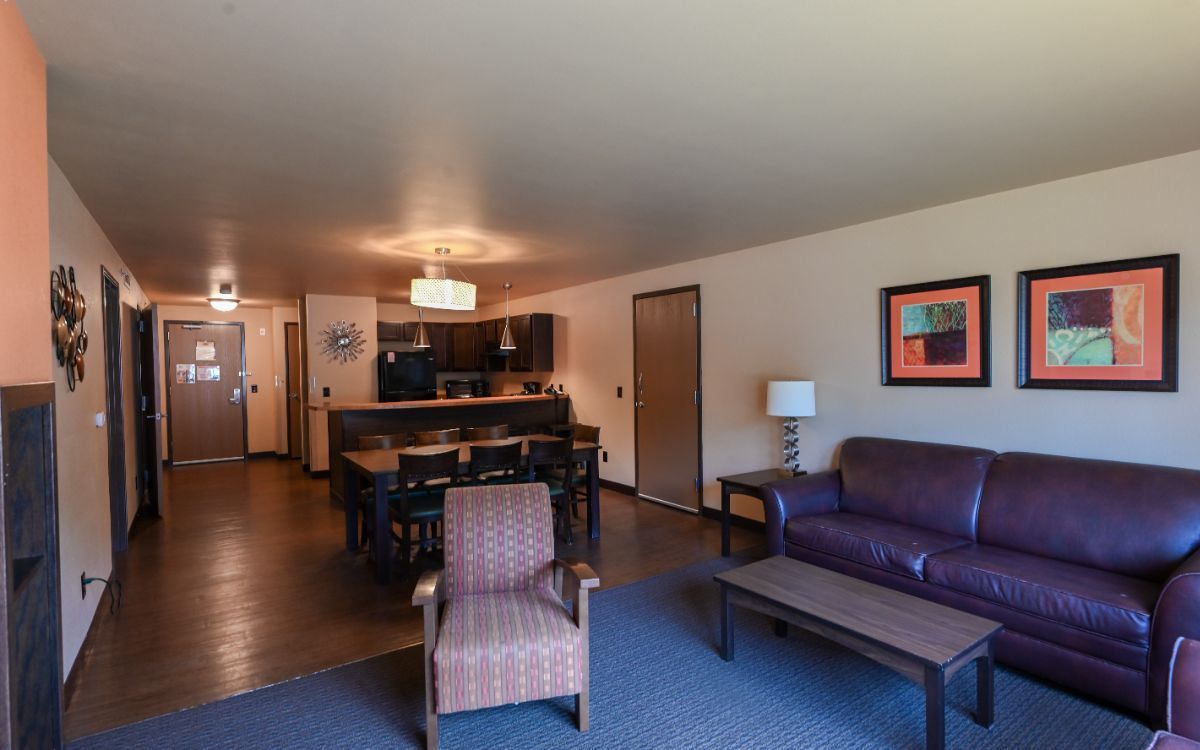 Spacious living area with dining table, kitchen, couch, and chair; brown, tan, and blue tones.