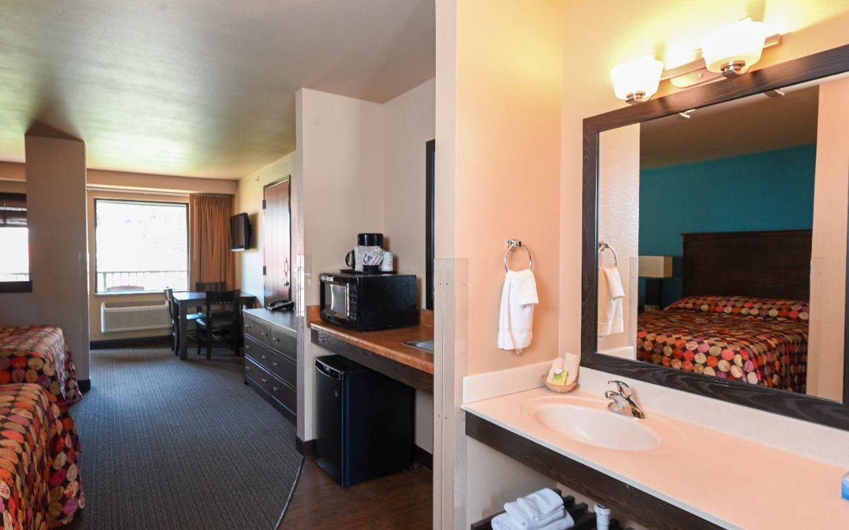 Hotel room with two beds, bathroom, desk, microwave, and mini-fridge.