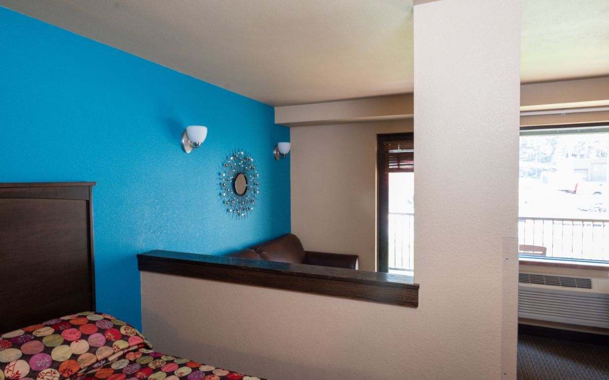 Hotel room with blue accent wall, decorative mirror, and partial divider.