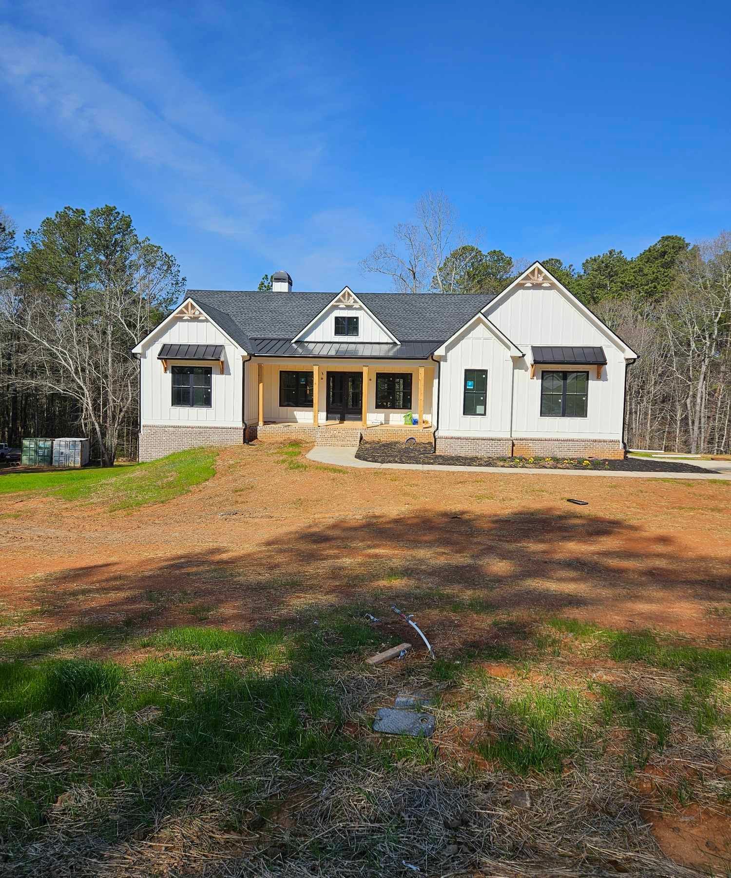 A large white house is sitting in the middle of a dirt field.