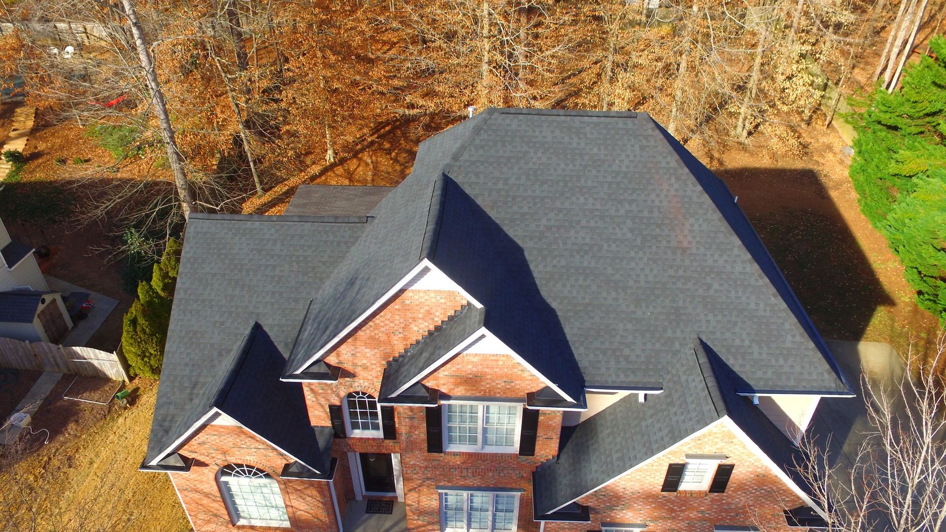 An aerial view of a large brick house with a black roof