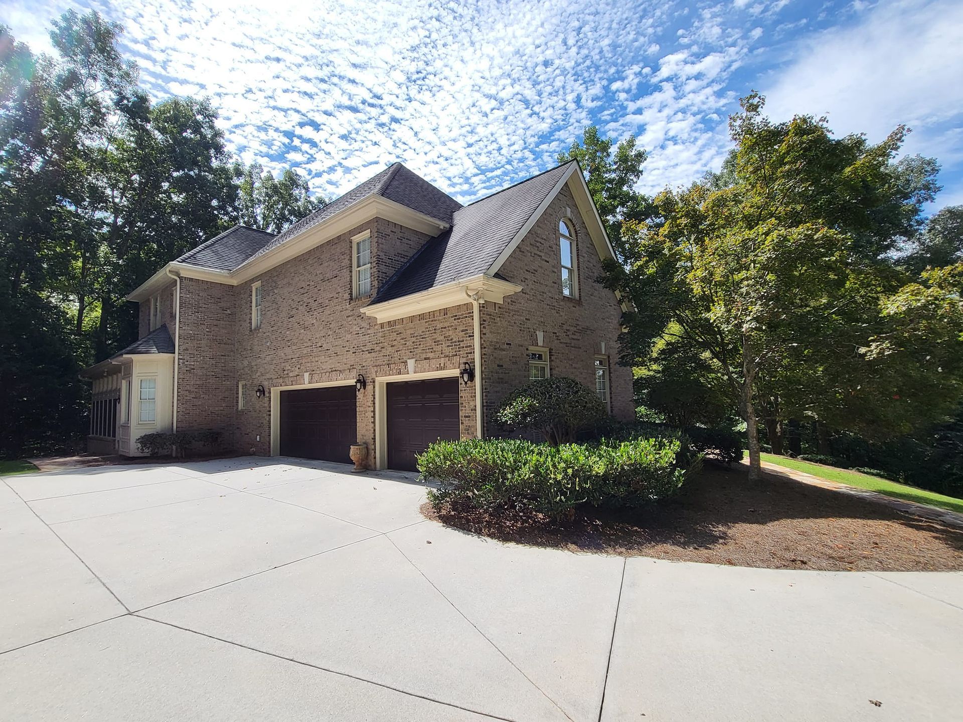 A large brick house with two garage doors and a driveway