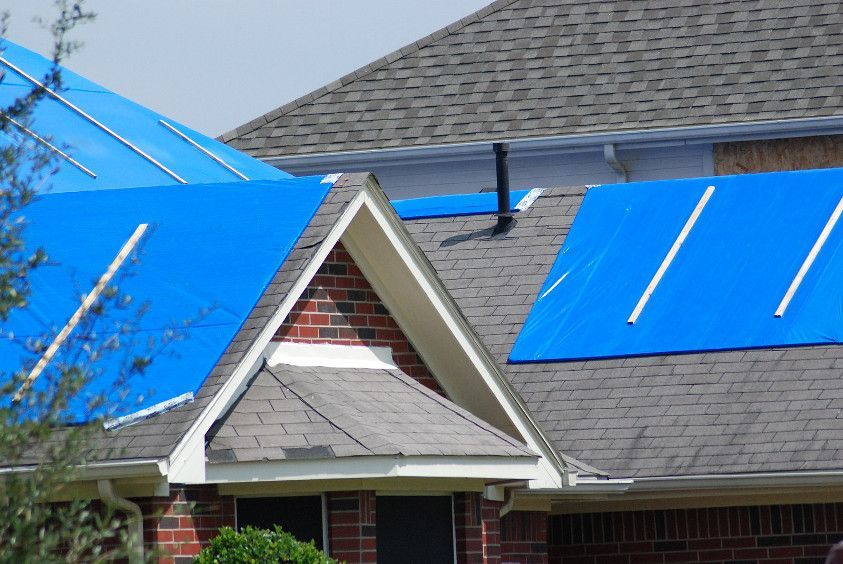 A blue tarp is covering the roof of a house