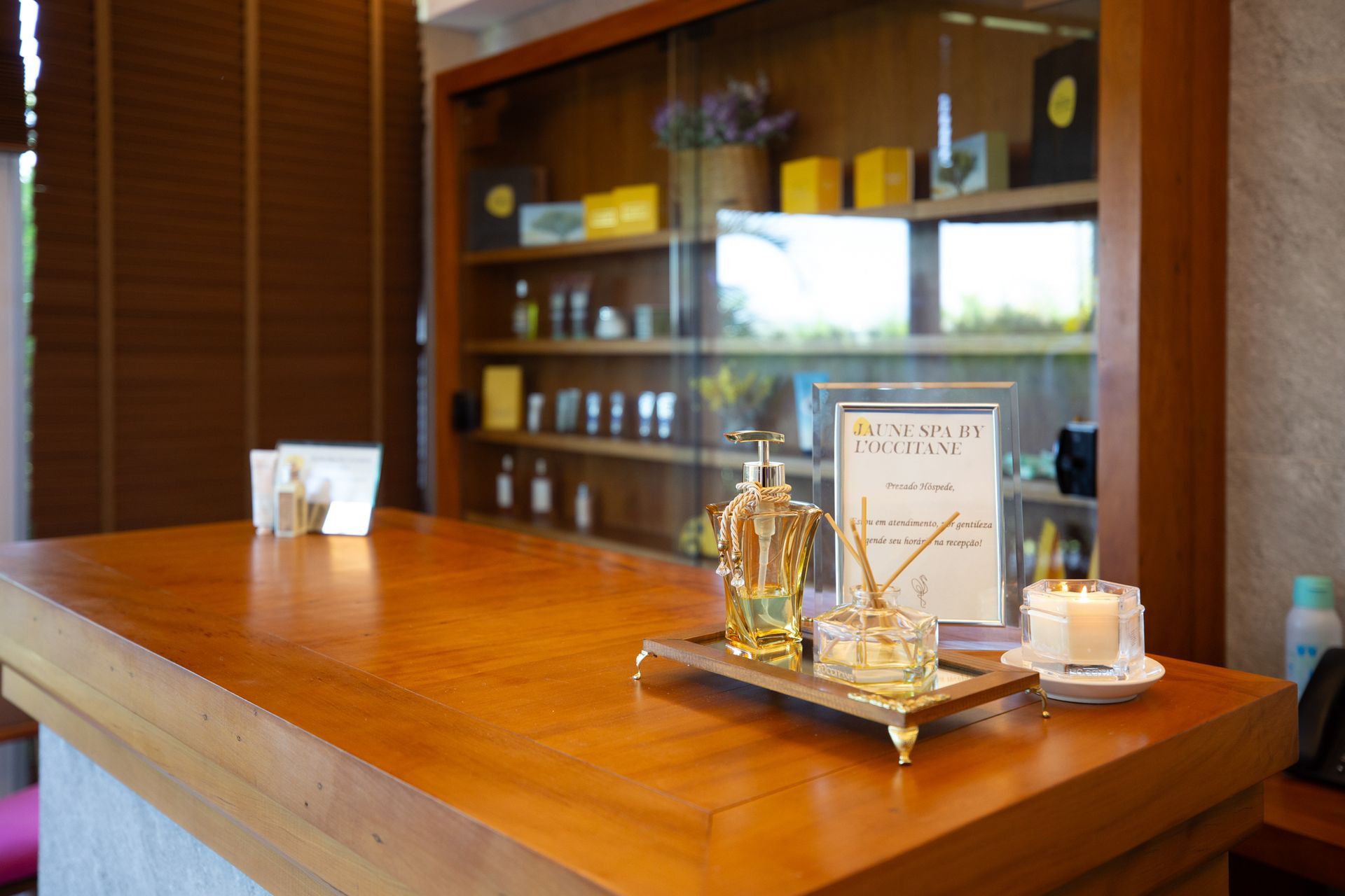 Velas, esfoliante corporal, incenso e flores em um banquinho de madeira, evocando um ambiente de spa.