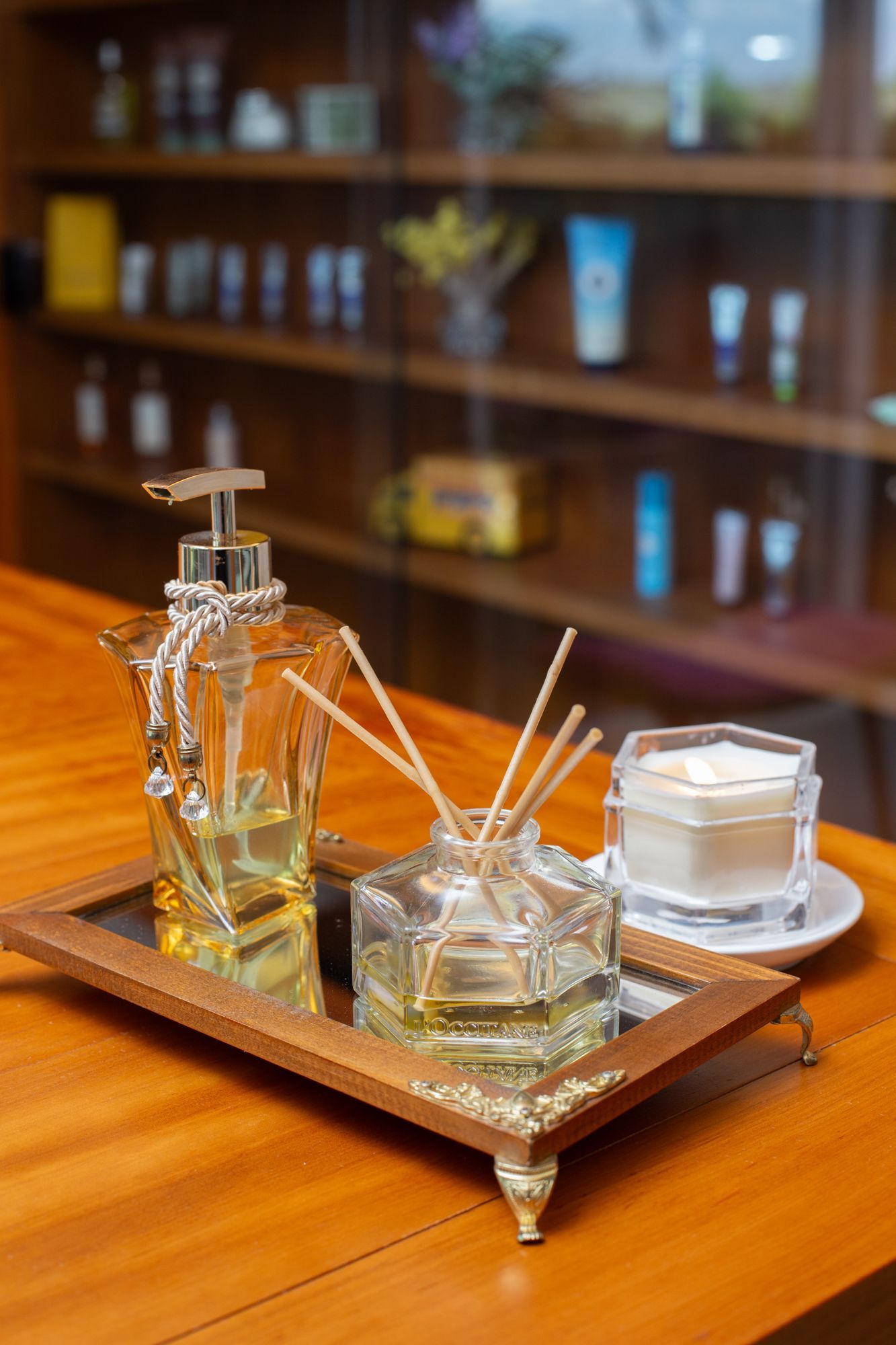 Velas, esfoliante corporal, incenso e flores em um banquinho de madeira, evocando um ambiente de spa.