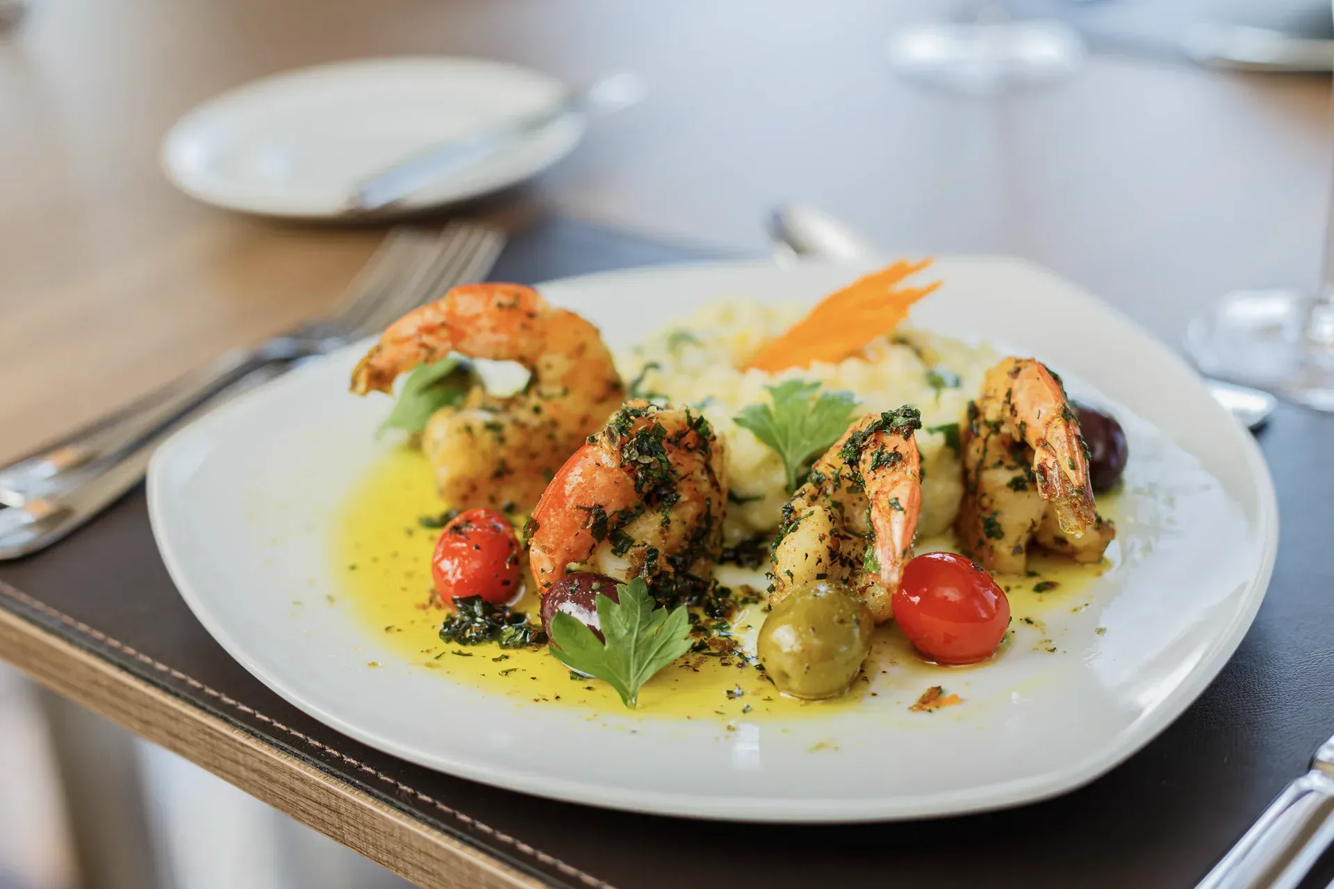 Pilha de panquecas com caramelo, morangos, nozes e chantilly em um prato branco.