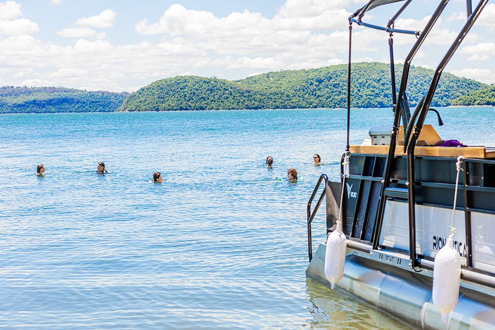Homem pratica stand up paddle na água, segurando o remo. Ele está de shorts e sem camisa.