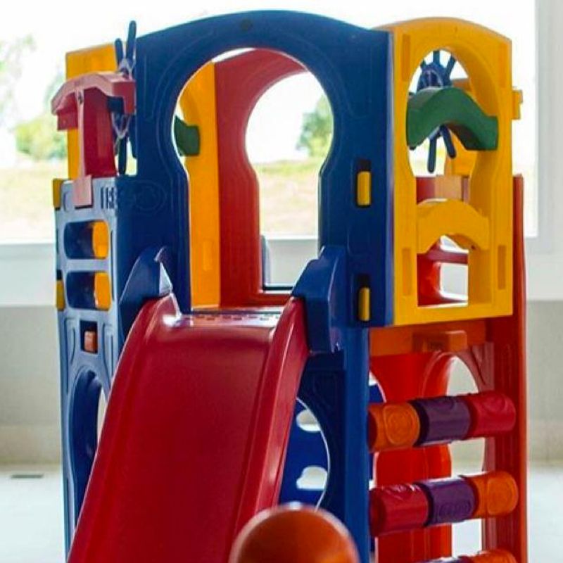 Conjunto de brinquedos de plástico multicolorido com escorregador, barras de escalada e volante.