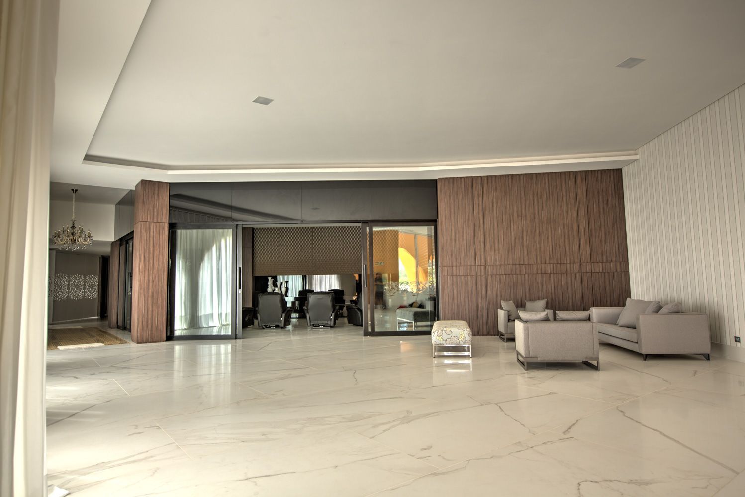 Interior espaçoso e moderno, com piso de mármore e áreas de estar. Possui paredes texturizadas e portas de correr de vidro.