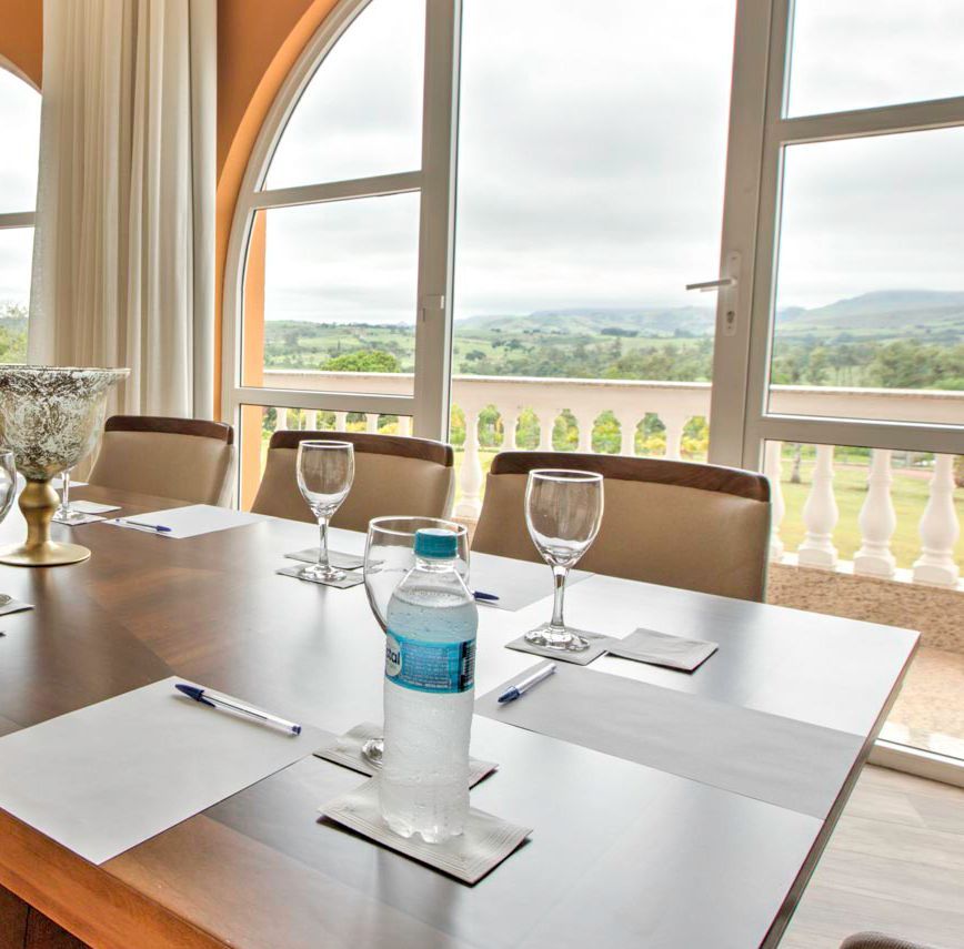 Sala de conferências com mesa posta para reunião, com vista panorâmica.