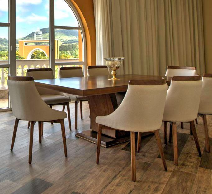 Sala de jantar com uma grande mesa de madeira, cadeiras creme e uma janela com vista panorâmica.