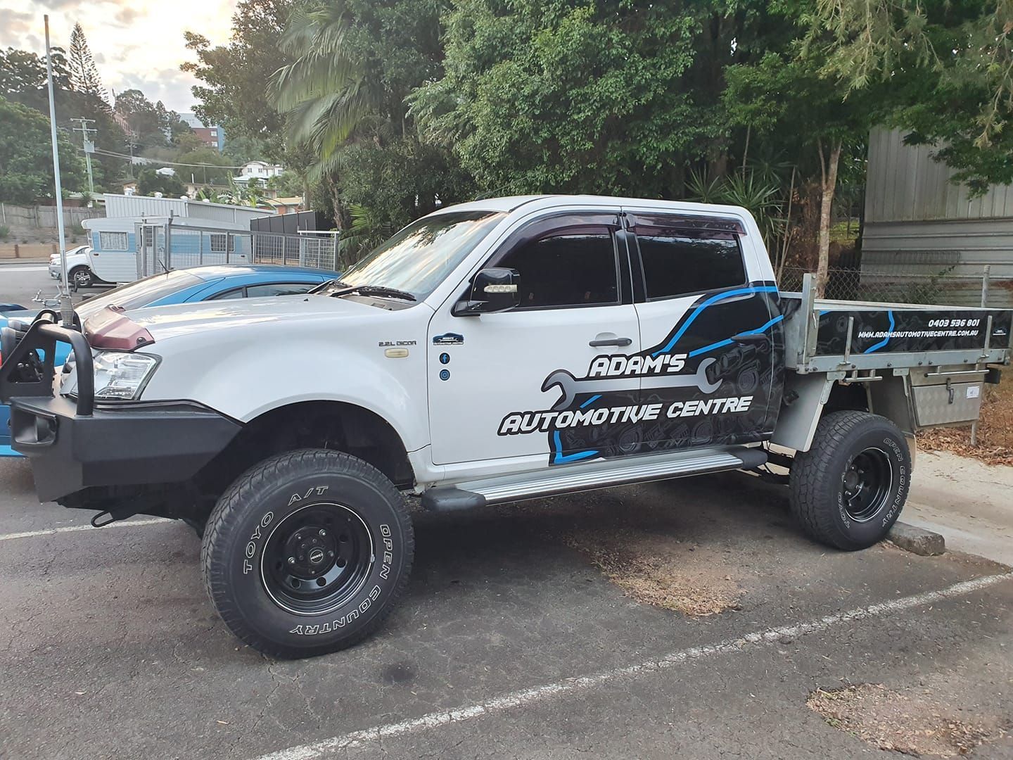 White pickup truck with business logo on the side, parked on asphalt.