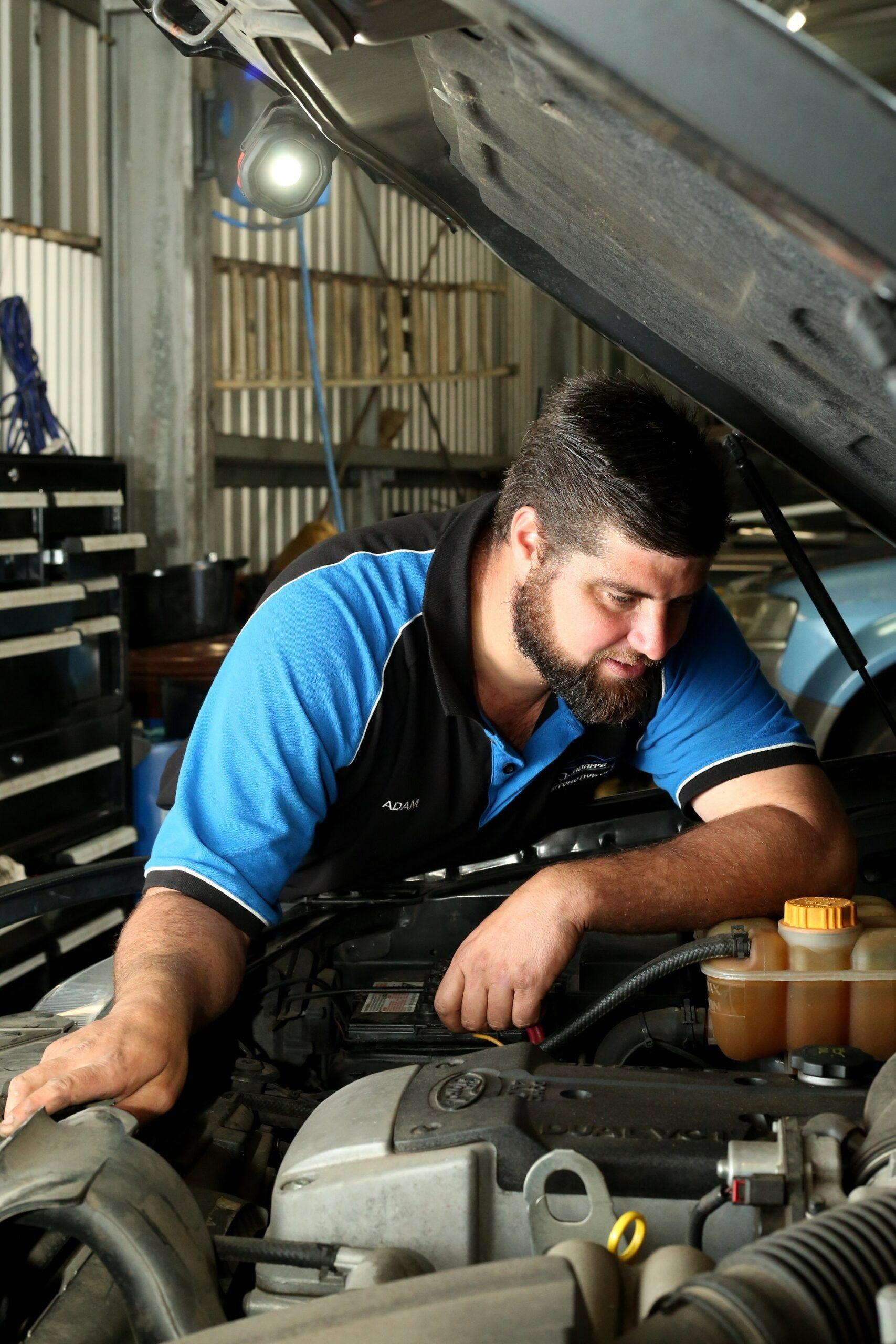 Mechanic in Blue Shirt Working on Car Engine in a Garage — Adam's Automotive Centre in Nambour, QLD