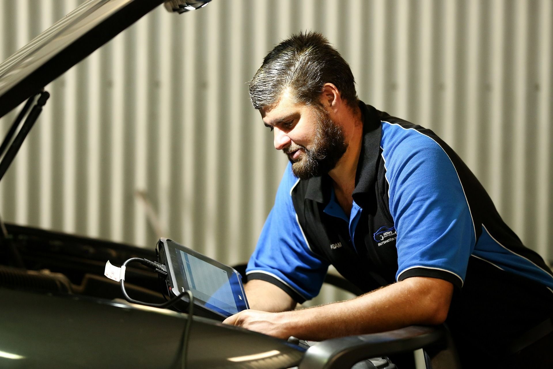 Mechanic Using a Tablet to Diagnose a Car Under the Hood in a Garage — Adam's Automotive Centre in Nambour, QLD