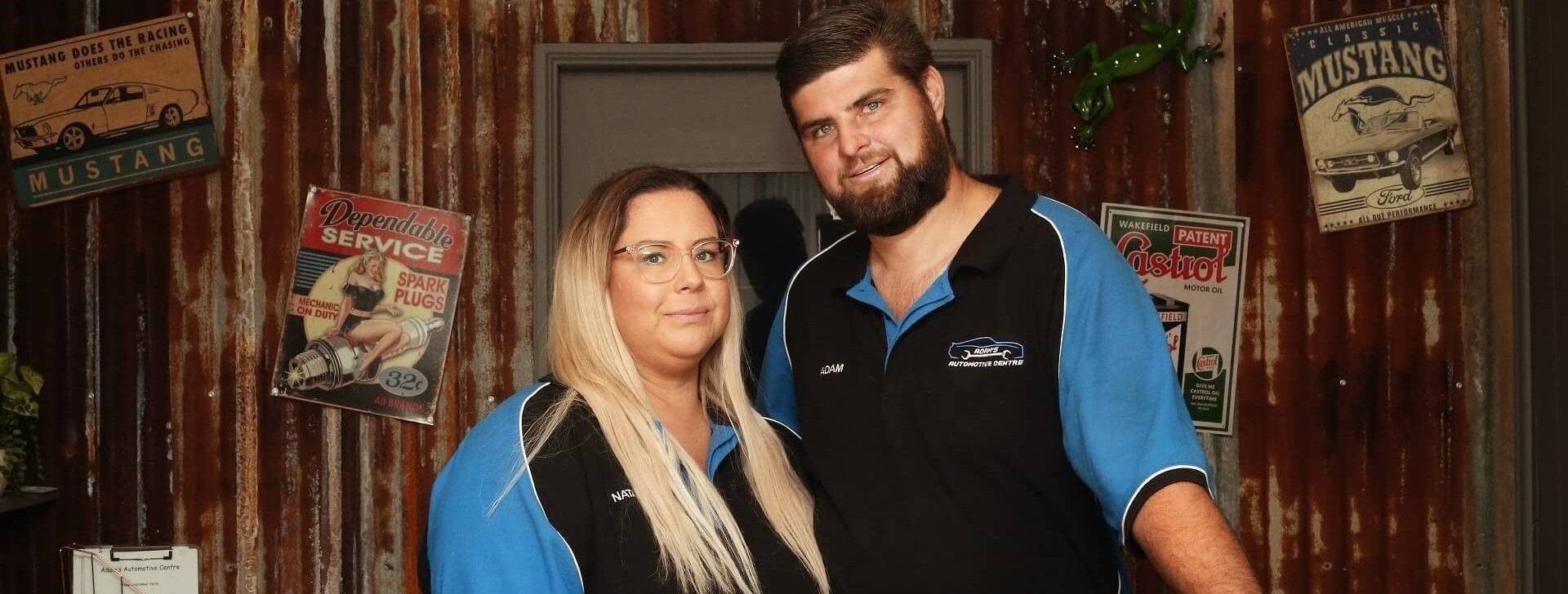 A Man and Woman Standing Close Together in Front of a Corrugated Wall — Adam's Automotive Centre in Nambour, QLD