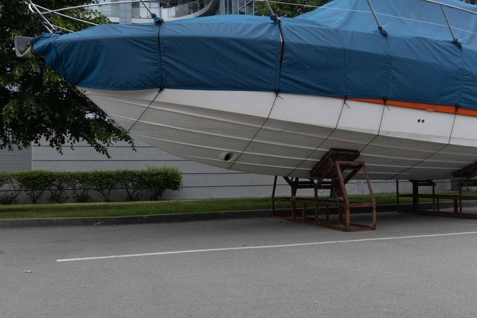 A boat with a blue cover is parked on the side of the road