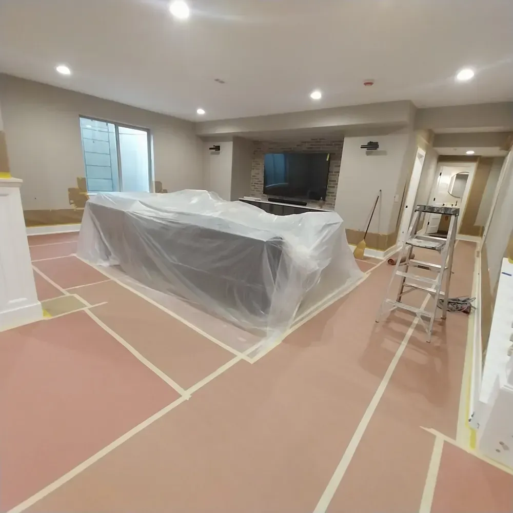 A living room with a couch covered in plastic and a ladder