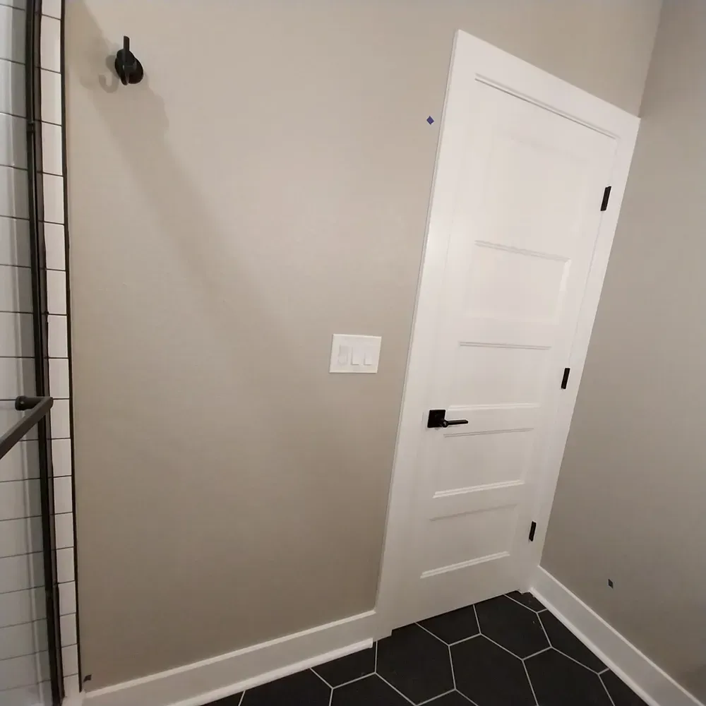 A bathroom with a white door and black tile floor