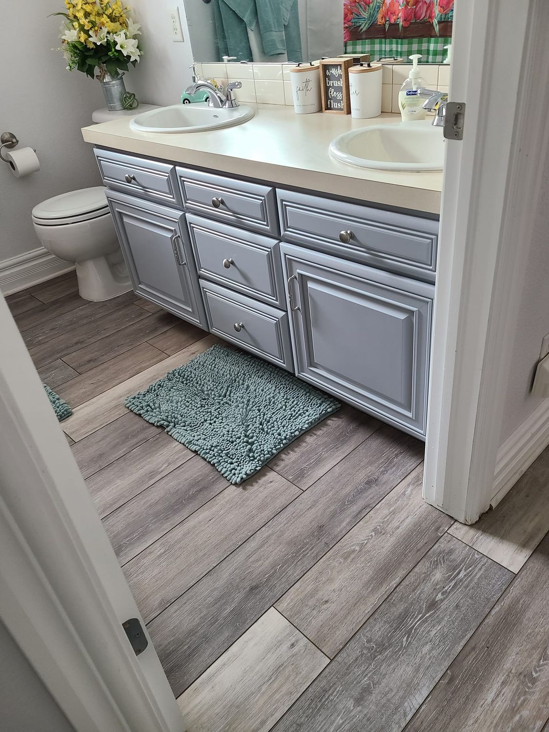 A bathroom with two sinks , a toilet , and a rug on the floor.