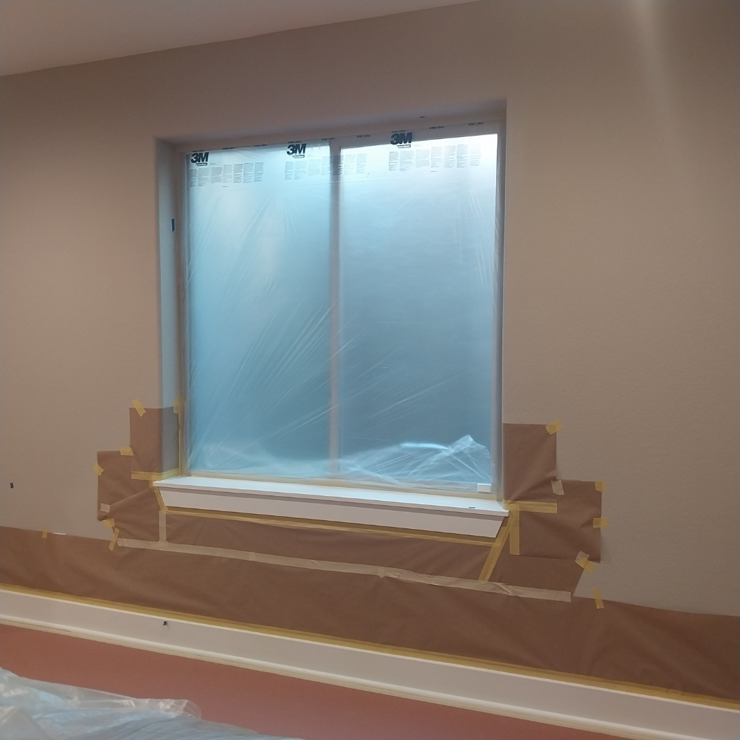 A room with a window covered in plastic and tape.