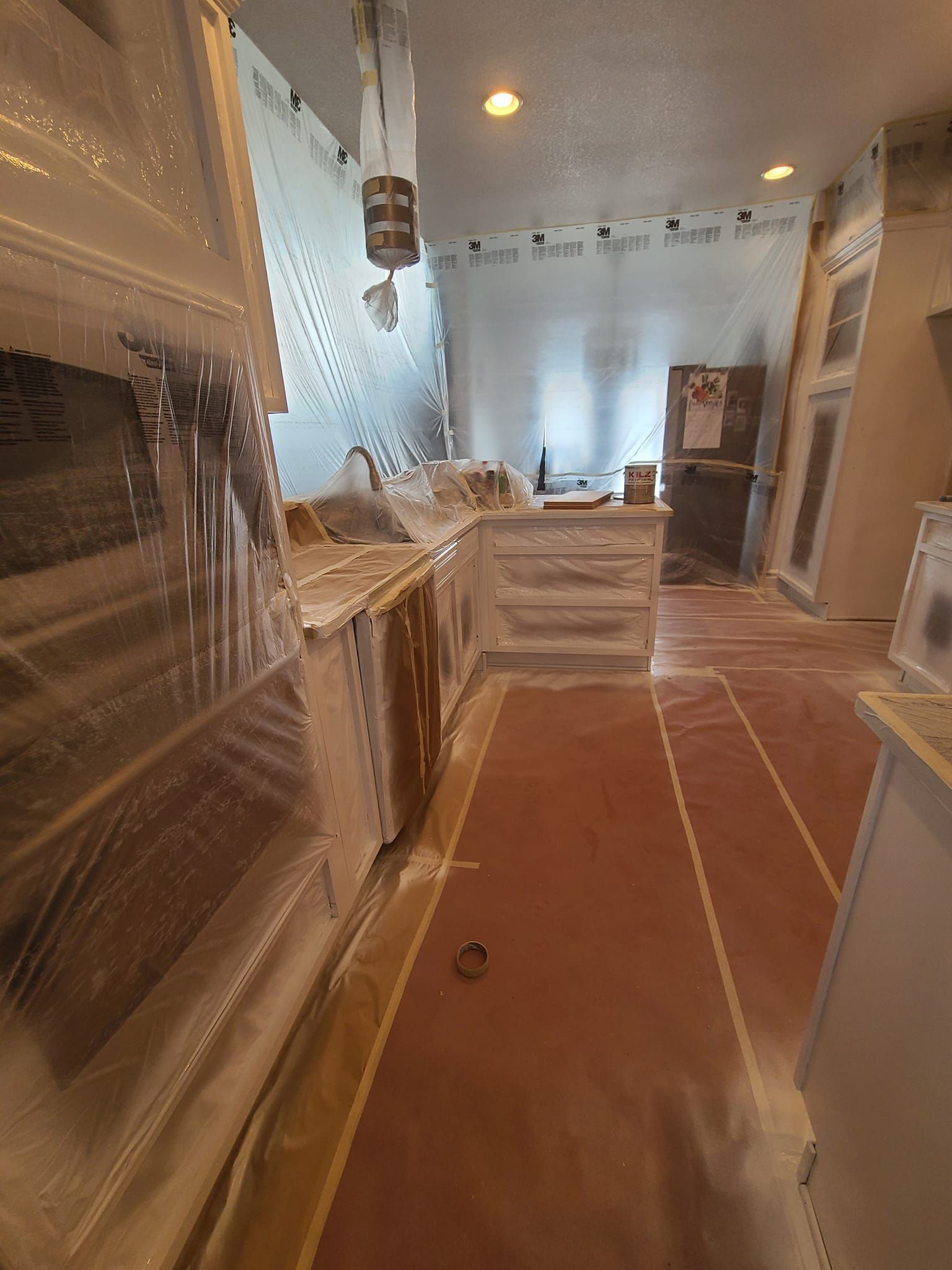 A kitchen is being painted and covered in plastic.