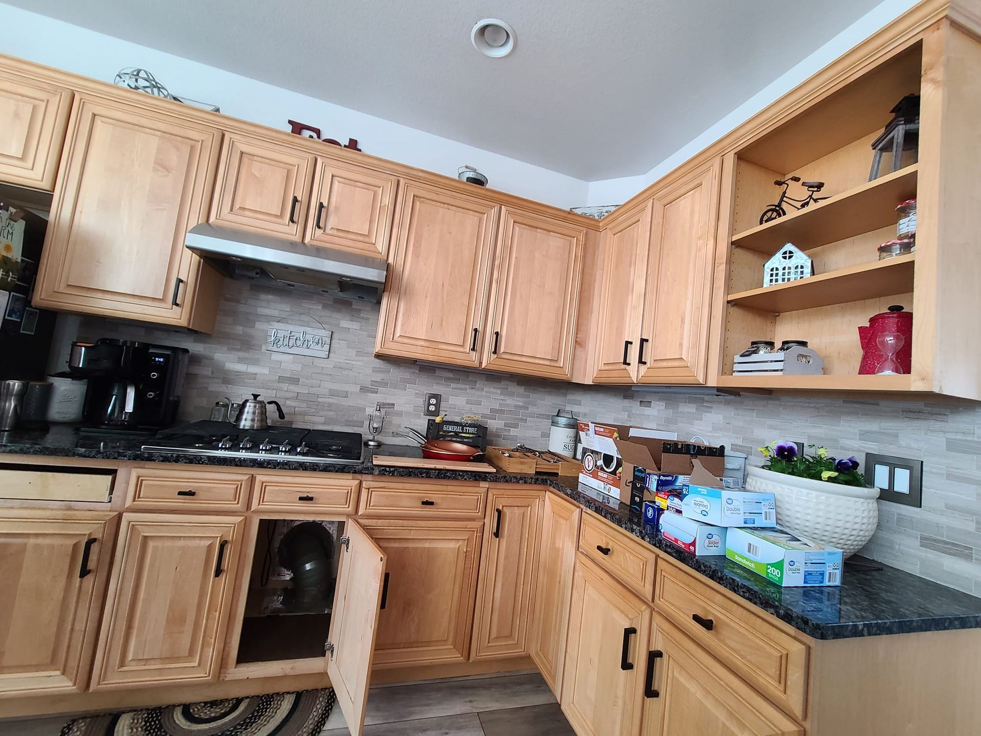 A kitchen with wooden cabinets and a black counter top
