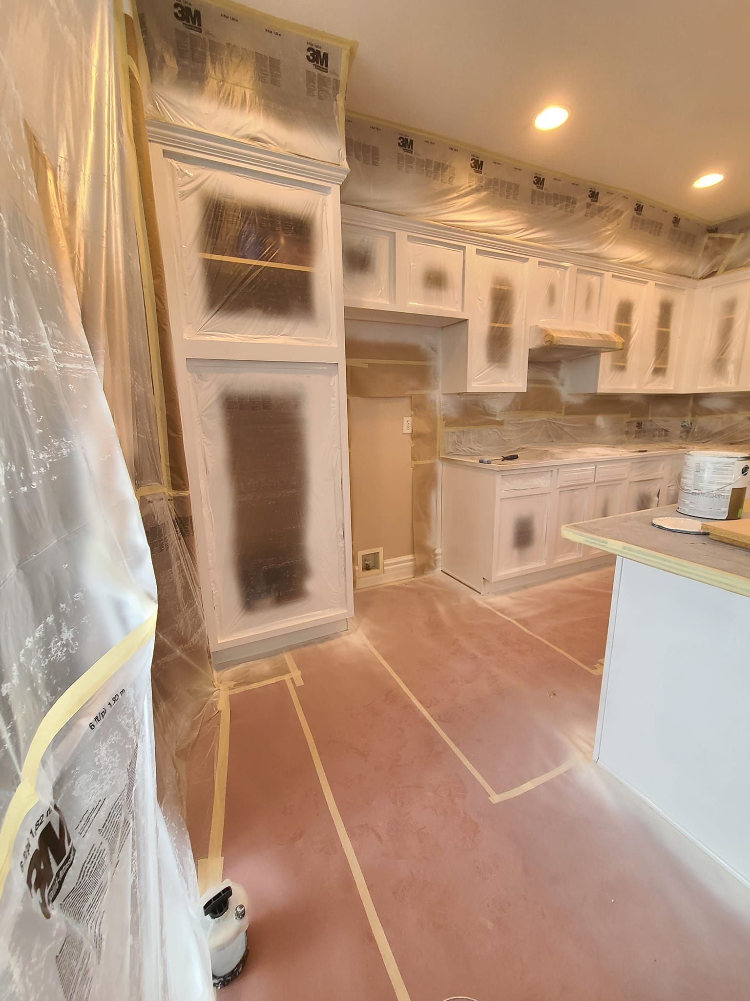 A kitchen is being painted and covered in plastic.