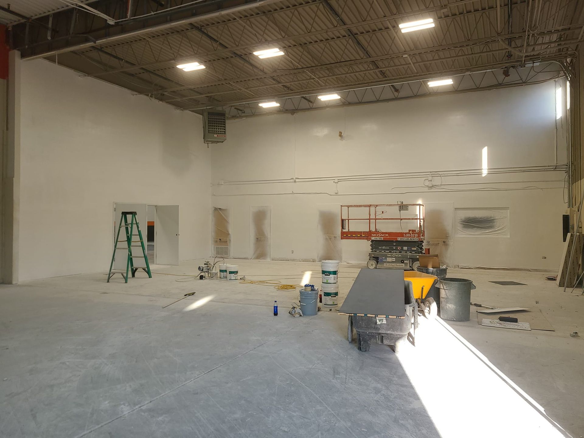 A large empty room with white walls and a ladder