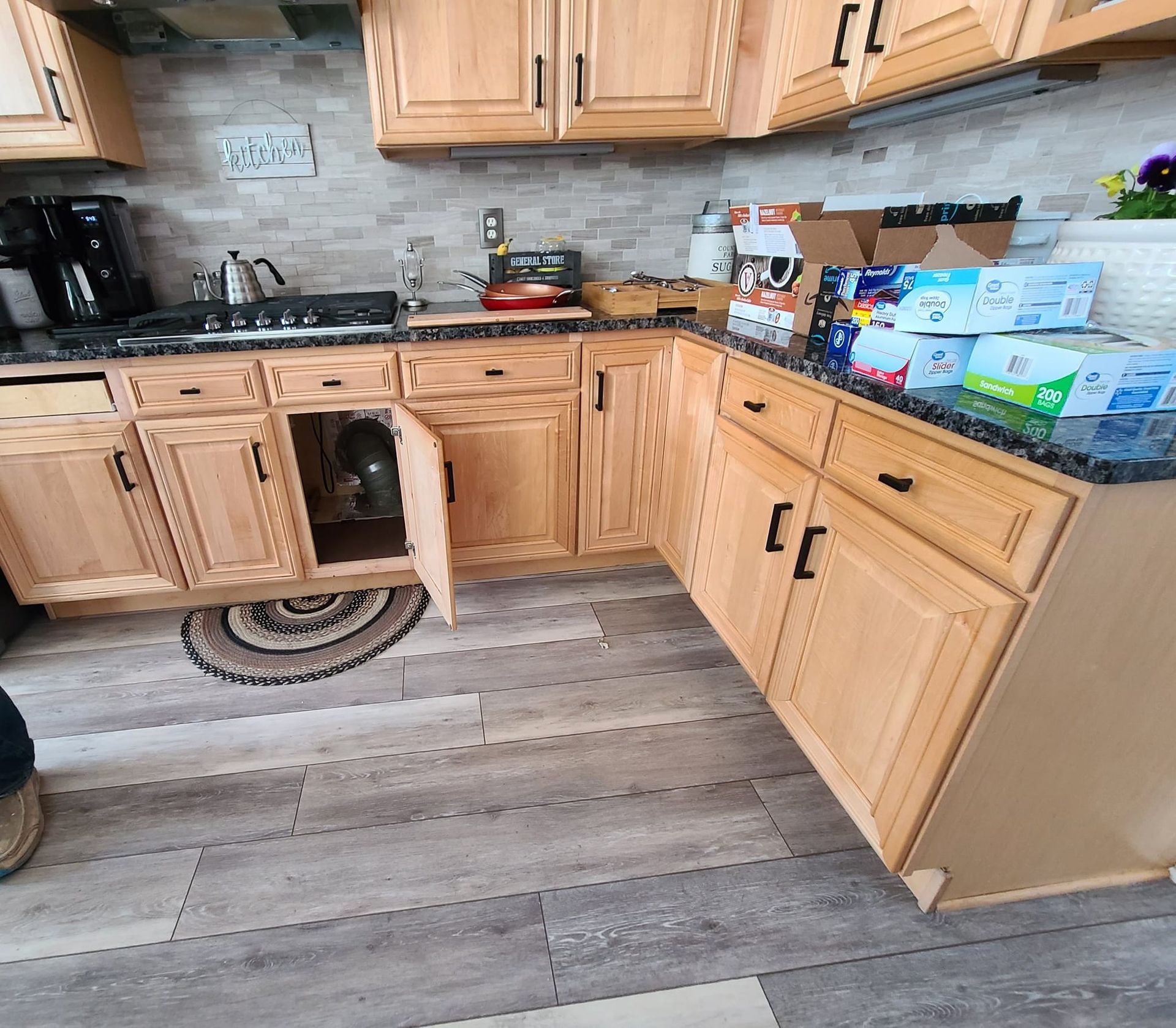 A kitchen with wooden cabinets , granite counter tops , and a sink.