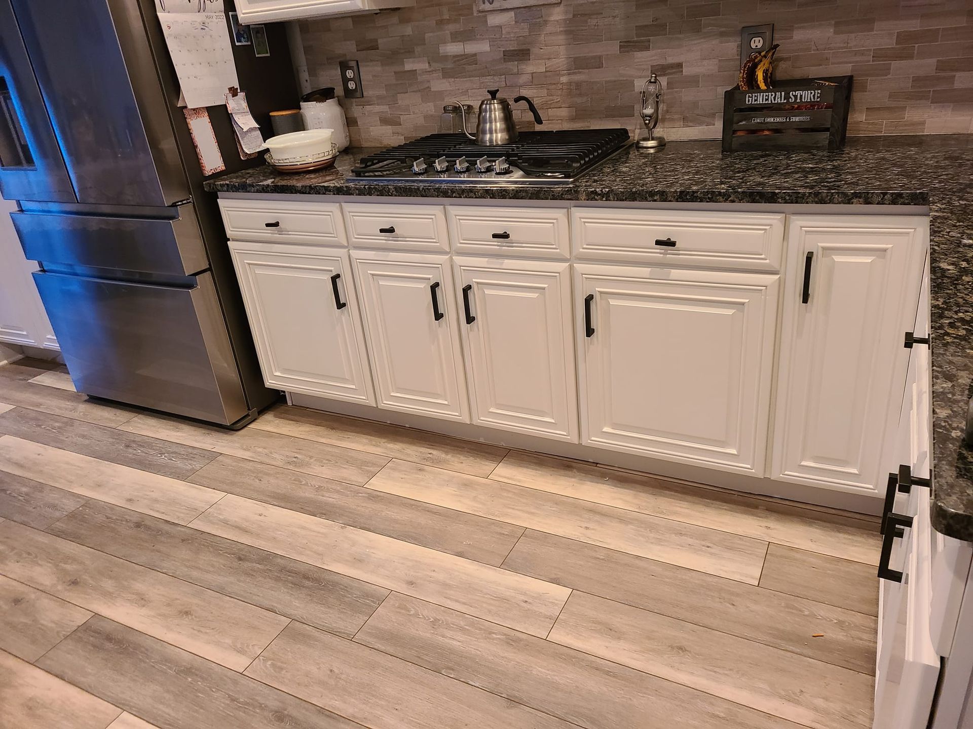 A kitchen with white cabinets and granite counter tops.