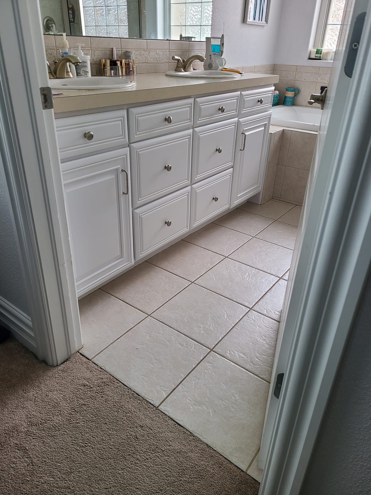 A bathroom with two sinks , a tub and a mirror.