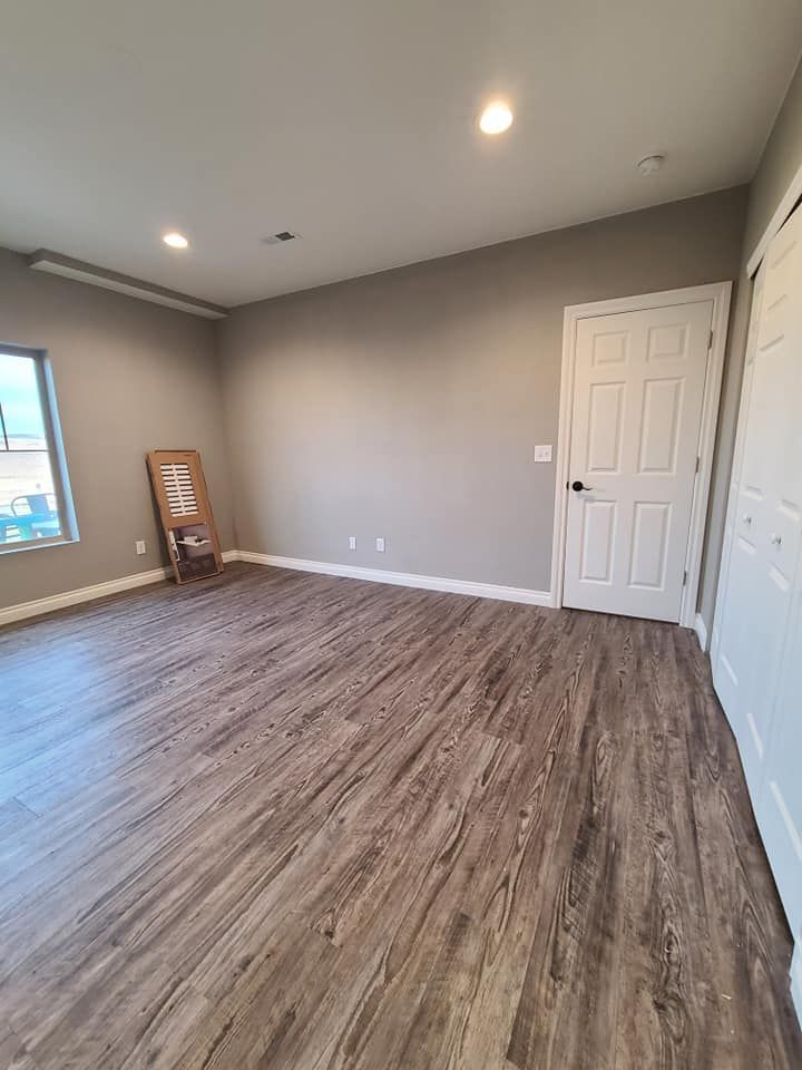 A large empty room with hardwood floors and a window.