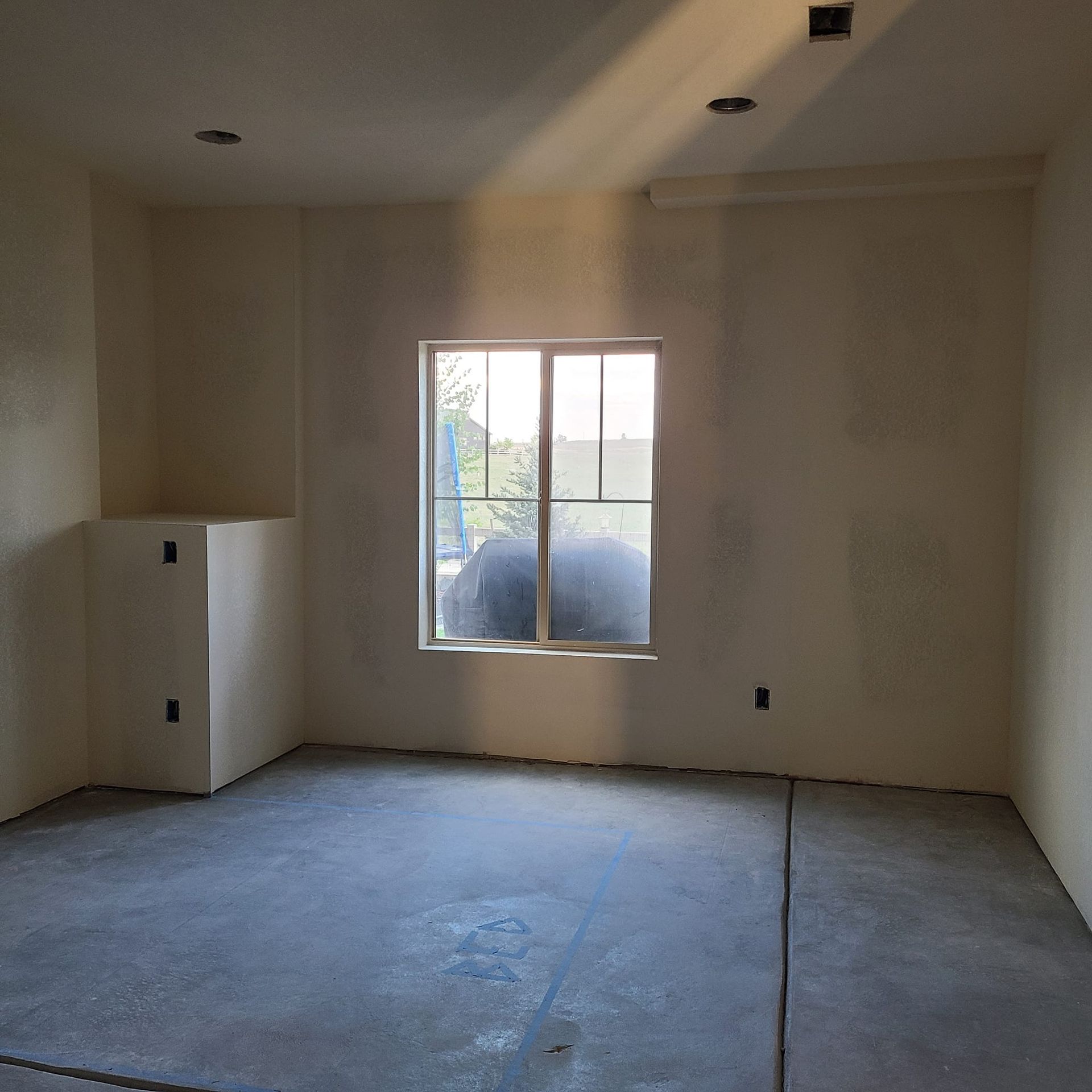 An empty room with a window and a concrete floor