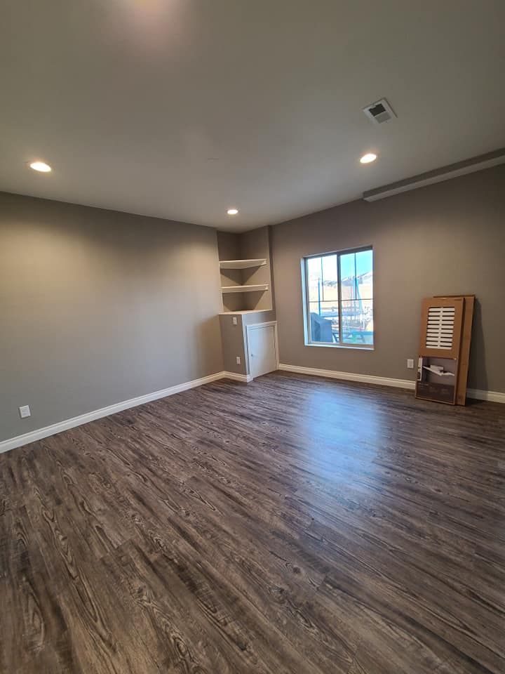 An empty living room with hardwood floors and a window.