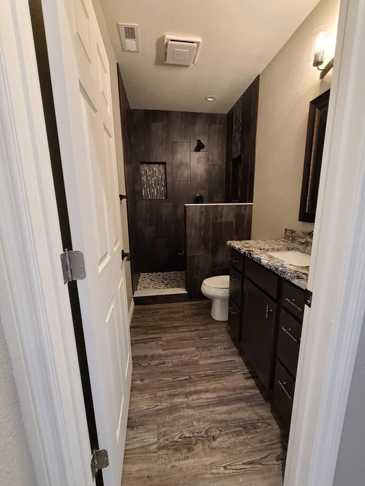A bathroom with a toilet , sink and shower.