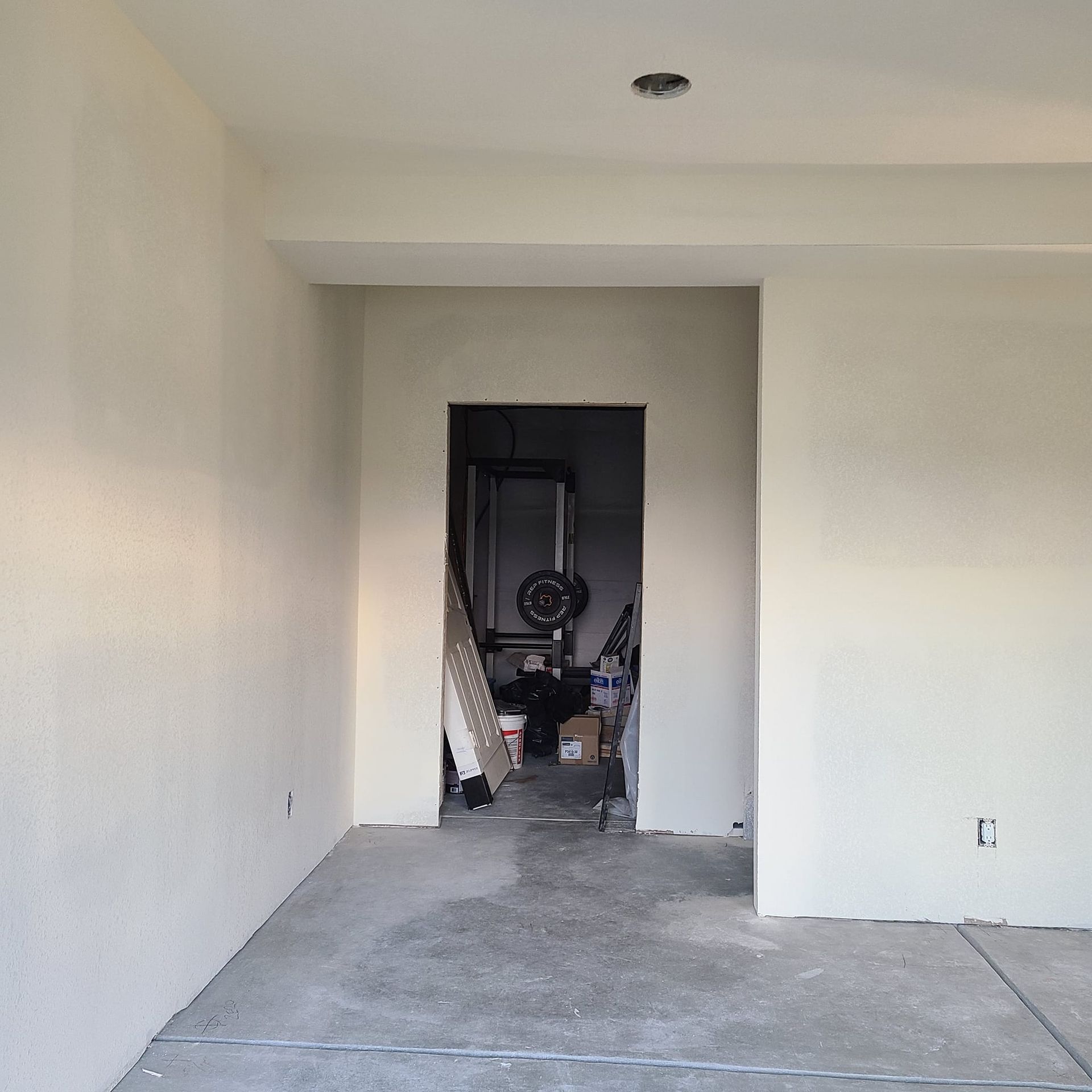 An empty room with white walls and a concrete floor