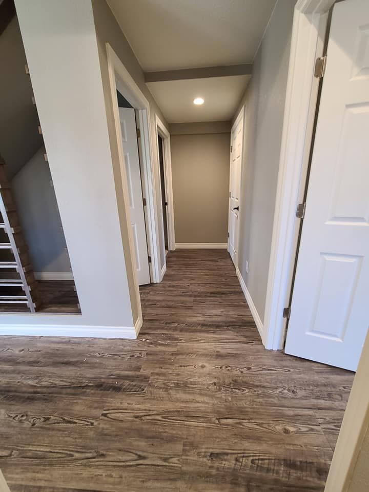 A hallway with hardwood floors and white doors in a house.