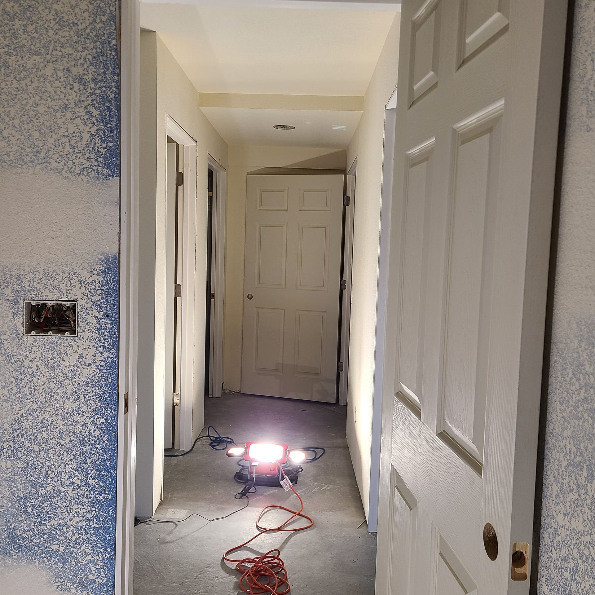 A hallway with white doors and a light on the floor